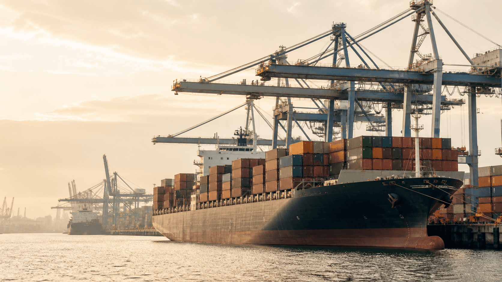 A freight ship loaded with containers moving through a working port